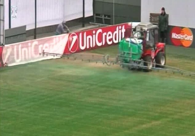 Сотрудник стадиона распыляет зеленую краску на поле